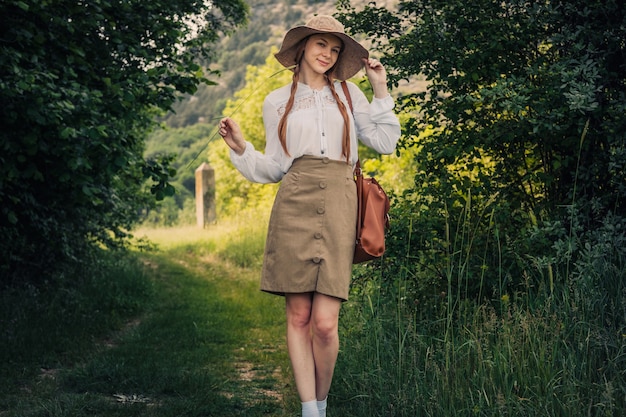 Viajante de mulher com mochila e chapéu andando em incríveis montanhas e florestas, conceito de viagens wanderlust, espaço para texto, momento atmosférico. Dia da Terra