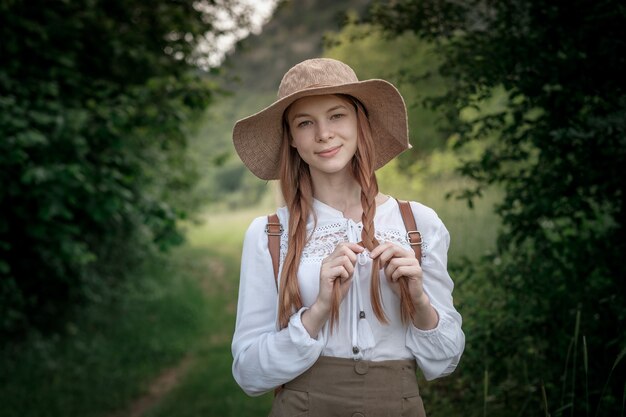 Viajante de mulher com mochila e chapéu andando em incríveis montanhas e florestas, conceito de viagens wanderlust, espaço para texto, momento atmosférico. dia da terra