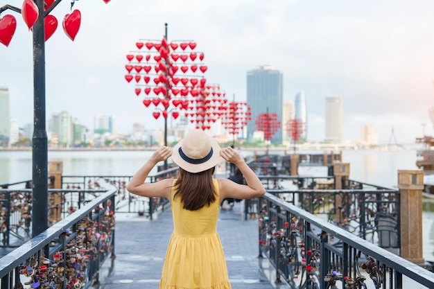 Foto viajante de mulher com vestido amarelo visitando da nang turismo turístico na ponte de bloqueio de amor marco e popular conceito de viagem no vietnã e sudeste asiático