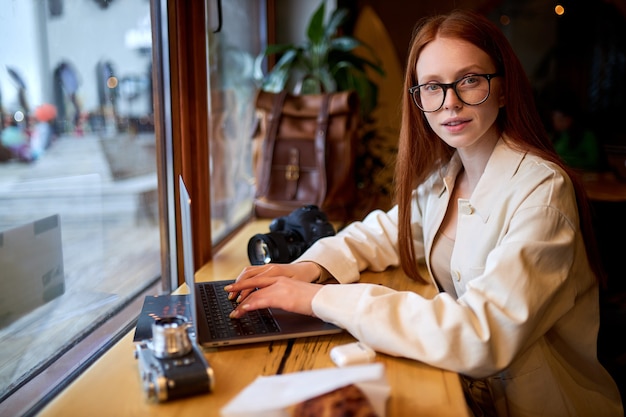 Viajante de mulher confiante usando laptop no café, trabalhando na cafeteria.