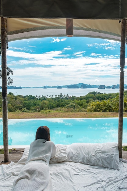 Viajante de mulher feliz desfruta de bela vista para o mar Turista relaxando em resort de luxo tropical com piscina Viagens de lazer e conceito de férias de verão