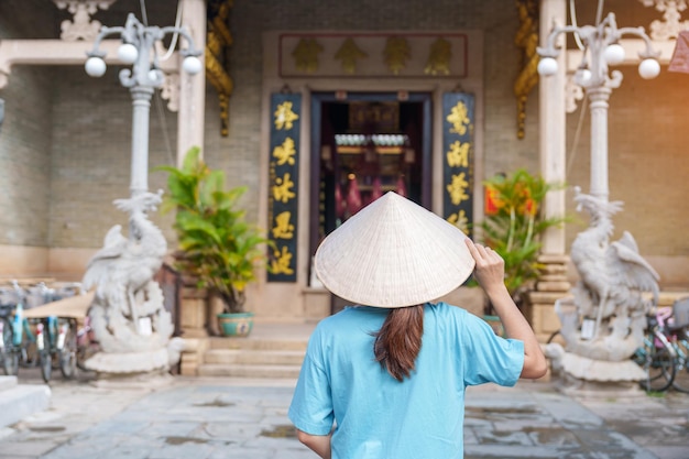 Viajante de mulher passeando em Phouc Kien Assembly hall tradução do caráter chinês A graça antiga da arquitetura de 300 anos Hoi An Vietnã e conceito de viagem do Sudeste Asiático