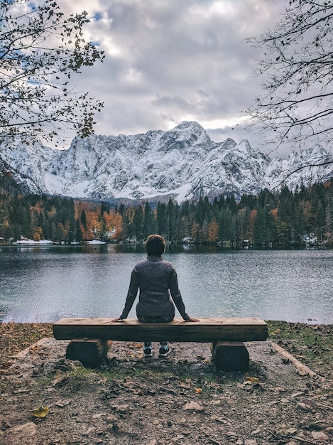 viajante de mulher senta-se no banco. admira a vista dos picos das montanhas cobertas de neve nos Alpes da Itália