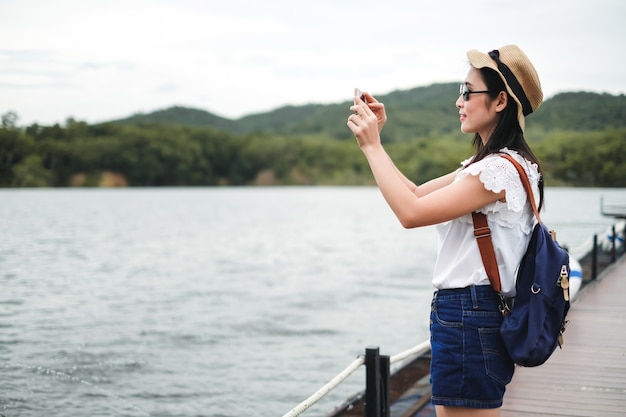 Viajante de mulher tirar foto vista da represa e montanha