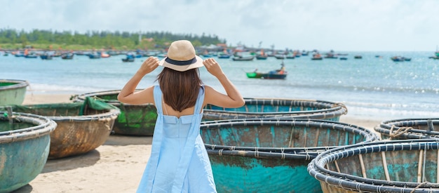 Viajante de mulher visitando a praia de My Khe e cesta de turismo terminando barcos Turista com vestido azul e chapéu viajando na cidade de Da Nang, Vietnã e conceito de viagem no Sudeste Asiático