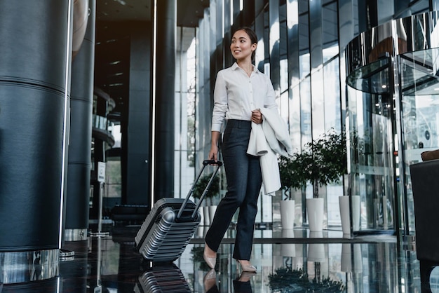 Viajante de negócios feminino asiático andando no corredor do aeroporto