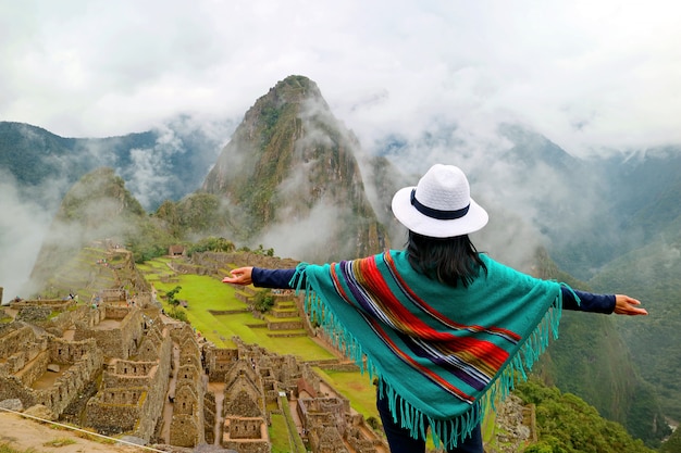 Viajante do sexo feminino, abrindo os braços para a antiga cidadela inca de Machu Picchu, região de Cusco no Peru