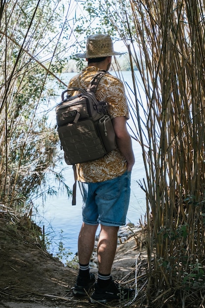 Foto viajante em frente a um rio entre vegetação