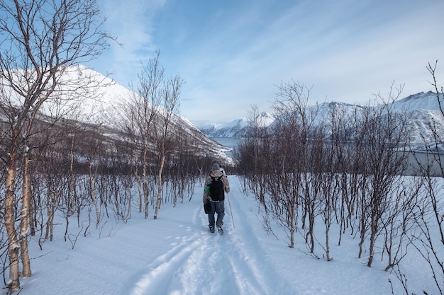 Viajante em grupo caminhando em uma colina de neve com céu azul ensolarado na ilha de senja, noruega