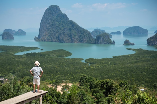 Viajante feliz desfruta do ponto de vista da baía de Phang Nga sozinho Turista em pé e relaxando em Samet Nang She perto de Phuket, no sul da Tailândia, viagem de viagem no Sudeste Asiático e conceito de férias de verão