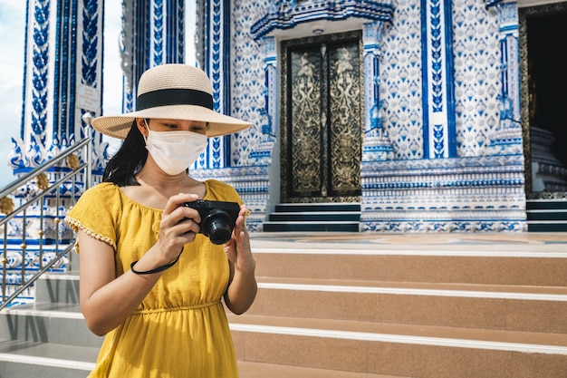 Viajante feliz mulher asiática com máscara e câmera para passear no templo Wat Pak Nam Khaem Nu, Chanthaburi, Tailândia