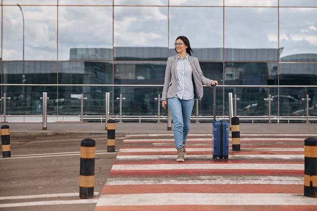 Viajante feliz mulher caucasiana no terminal do aeroporto com bagagem