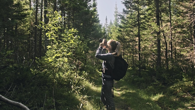 Viajante fotografando a vista panorâmica na floresta Uma mulher caucasiana atirando um belo olhar mágico Garota tira um vídeo fotográfico na câmera dslr mirrorless