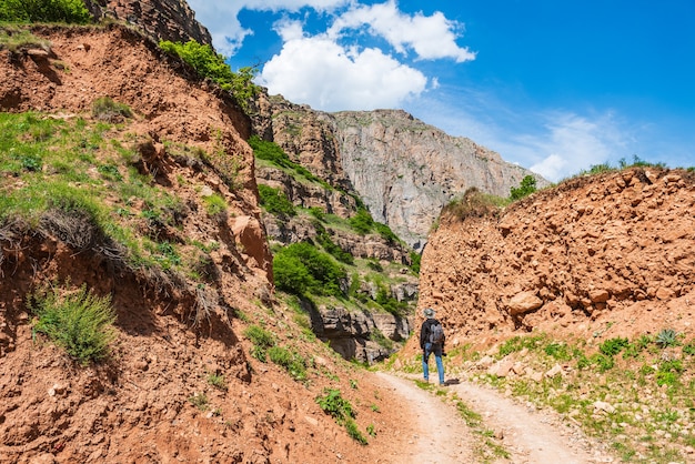 Viajante fotógrafo com câmera e mochila caminhando em uma estrada de terra nas montanhas