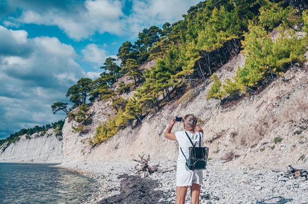 Viajante idoso, mochileiro, mulher madura, turista, caminhando, tirando fotos na costa