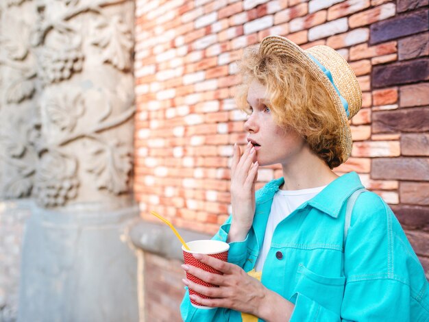 viajante jovem alegre ruiva encaracolada segurando uma xícara de café e surpreso com os pontos turísticos