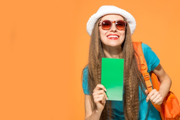 viajante jovem com mochila usando chapéu e óculos escuros, segurando o cartão verde