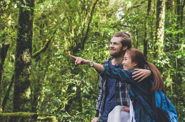 Foto viajante jovem hipster casal com mochila caminhadas na floresta verde