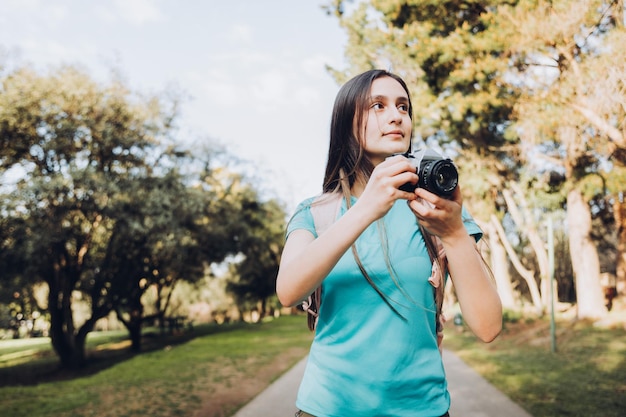 Viajante jovem turista, vestindo camiseta e uma mochila tirando fotos enquanto caminhava no parque