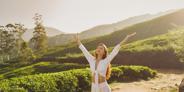 Viajante positivo da mulher contra a paisagem natural das plantações de chá