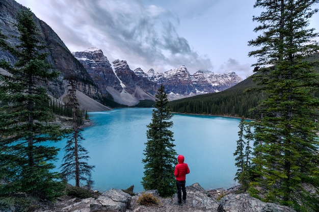 Viajante que está na rocha com montanhas rochosas canadenses na manhã no lago Moraine