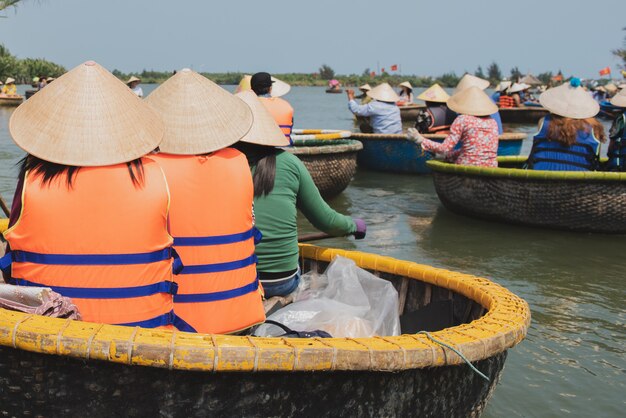 Viajante que senta-se no barco de bambu tradicional da cesta de vietname no canal no da nang, vietname.