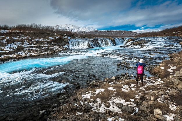 Foto viajante tirando foto da cachoeira de bruarfoss na temporada de inverno