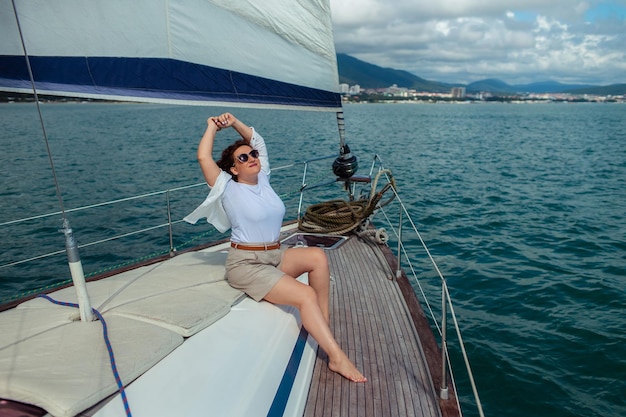 Viajante turista de mulher em óculos de sol em um dia de verão em um iate no mar