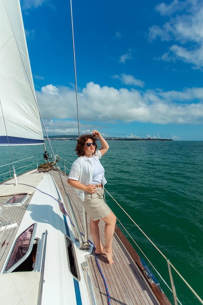 Viajante turista de mulher em óculos de sol em um dia de verão em um iate no mar