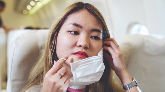 Viajante usando máscara facial durante uma viagem em avião comercial.