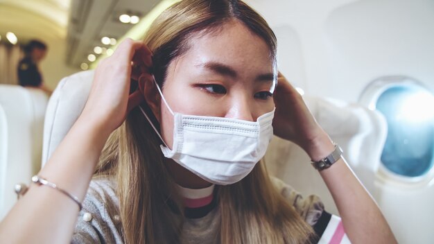 Viajante usando máscara facial enquanto viaja em um avião comercial