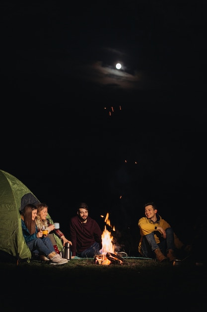 Viajantes amigos sentados em frente à fogueira à noite