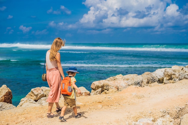 Viajantes de mãe e filho na incrível Melasti Beach com água turquesa Bali Island Indonésia Viajando com o conceito de crianças