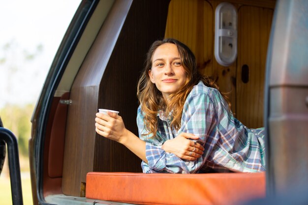 Viajantes de mulher bonita caucasiana feliz desfrutam de café de manhã na natureza, férias em um carro de acampamento