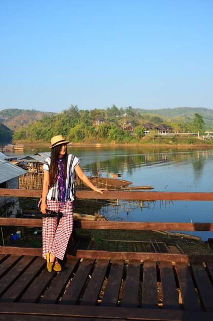 Foto viajantes mulheres tailandesas viajam visita e retrato posando para tirar foto na ponte de madeira mais longa de saphan mon ou uttamanusorn cruzando o rio mae klong na cidade de sangkhla buri em kanchanaburi tailândia