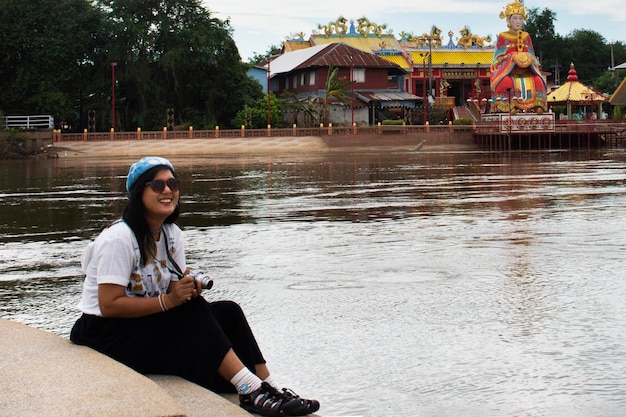 Viajantes mulheres tailandesas viajam visitam a ponte pa san ou pasan e tiram fotos na beira do rio chao phraya com o santuário da deusa chinesa chao mae thapthim em 28 de outubro de 2022 em nakhon sawan tailândia