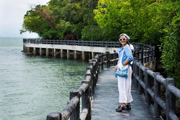 Viajantes mulheres tailandesas viajam visitam e caminham posando retrato na ponte de pedra da zona de viagem no tempo no oceano marítimo do Parque Nacional Mu Ko Petra na vila de Pak Bara na cidade de La ngu em Satun Tailândia