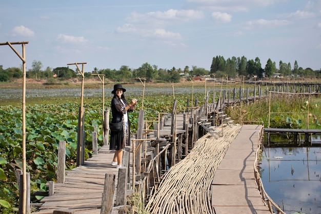 Viajantes tailandeses viajam visitam e posam retrato para tirar foto na ponte de madeira longa Kae Dam na zona rural em 11 de janeiro de 2019 em Maha Sarakham Tailândia