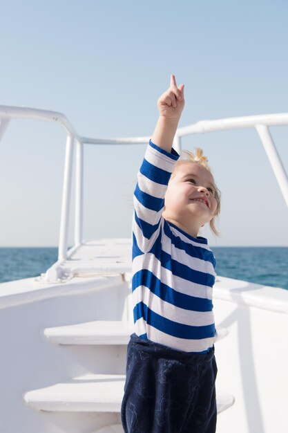 Viajar aventuras y pasión por los viajes verano viajar vacaciones infancia felicidad feliz niño pequeño en yate barco viajando por mar pequeño marinero en barco niño divertido en camisa marina a rayas