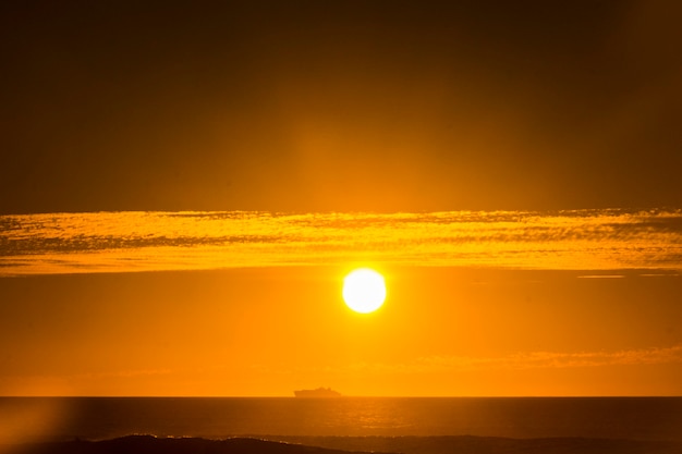 Viajar en barco de crucero por concepto de vacaciones con horizonte y gran sol naranja en backgorund