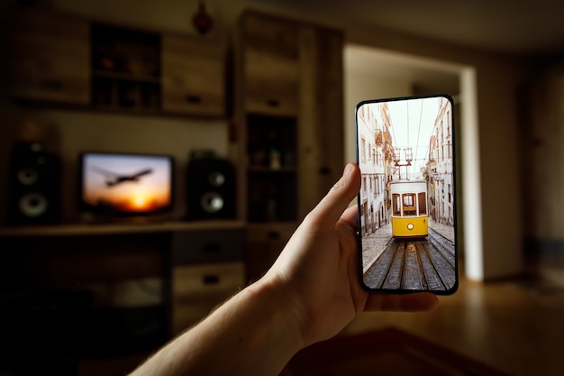 Viajar em casa. viagem online a lisboa, portugal via smartphone. lendário bonde amarelo na tela