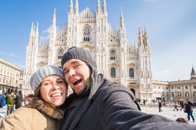 Viajar fotografiando y concepto de personas pareja feliz tomando autorretrato en milano en la plaza del duomo