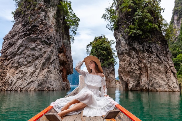 Viajar mujer sentada en un barco cerca de las famosas tres rocas en el parque khao sok de tailandia