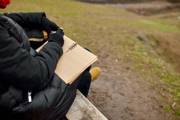 Viajar mujer con sombrero rojo en chaqueta negra escribir en el cuaderno, tomar notas