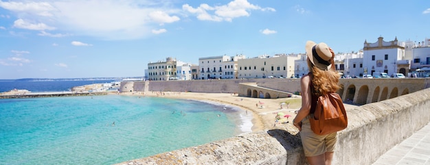 Viajar na Itália. Vista panorâmica do mochileiro feminino com chapéu na aldeia de Gallipoli, Salento, Itália.