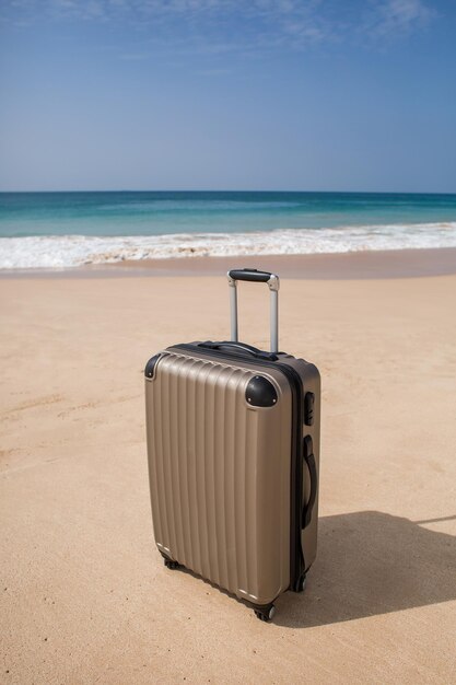 Viajar no verão e planejamento turístico com mala amarela com moda de chapéu amarelo na bela praia Viajar em férias Céu azul e fundo de areia em viagens no conceito de verão