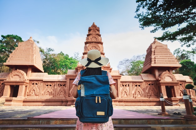 Viajar solo relajarse concepto de vacaciones, joven viajero asiático feliz y fotógrafo mujer con cámara y mochila turismo en el templo Wat Tham Phu wa, Kanchanaburi, Tailandia