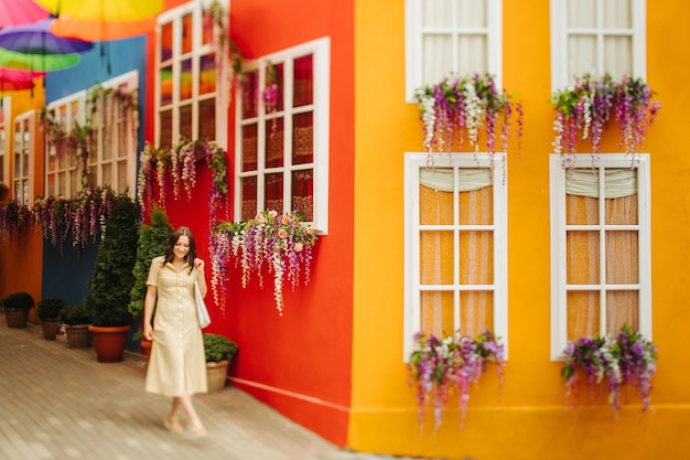 Viajar turista mujer morena con vestido amarillo camina por las calles con una decoración brillante de la ciudad. Desenfoque de la lente de cambio de inclinación