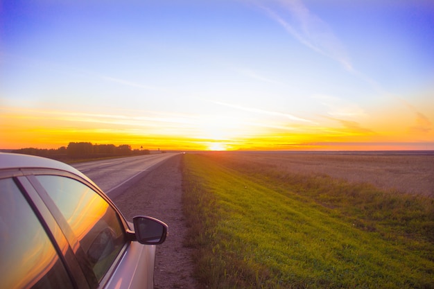 Viaje al atardecer. La pista se adentra en un atardecer anaranjado. el coche está en la carretera