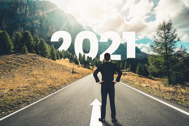 El viaje del Año Nuevo 2021 y el concepto de visión futura. Hombre de negocios viajando por la carretera que conduce a la celebración del feliz año nuevo a principios de 2021 para un comienzo nuevo y exitoso.